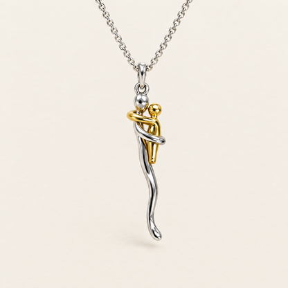 Knuffelketting: zilveren figuur die een klein gouden figuurtje omarmt, aan een zilverkleurige ketting